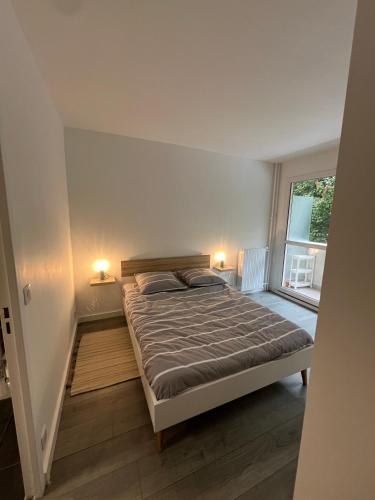 une chambre avec un lit avec deux lampes et une fenêtre dans l'établissement Oasis de Verdure avec Balcons - Proche Versailles, à Viroflay