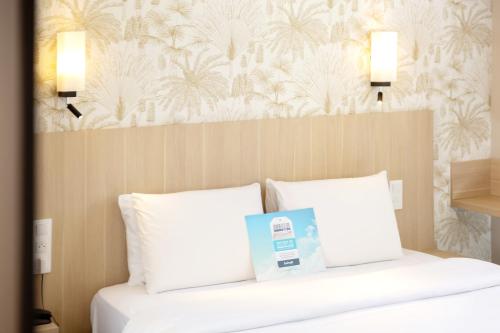a hotel room with a bed with a book on it at Kyriad Avignon - Palais des Papes in Avignon