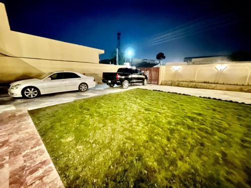 two cars parked in a parking lot next to a green lawn at Shelton Hotel Mardan in Mardan