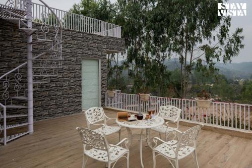 a patio with a table and chairs on a deck at StayVista at Silver Slopes with outdoor pool in Chandīgarh