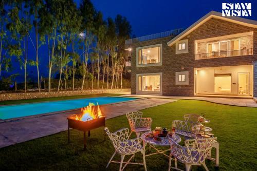 a backyard with a fire pit and chairs and a pool at StayVista at Silver Slopes with outdoor pool in Chandīgarh