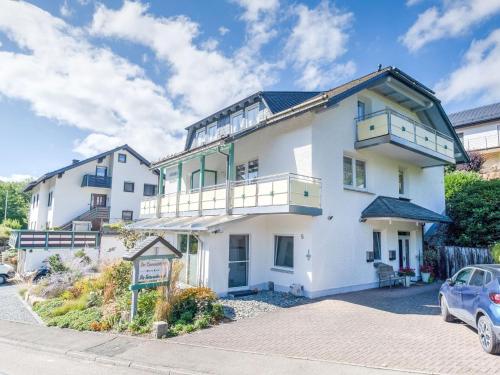 uma grande casa branca com um carro estacionado na frente em Modern Apartment in Schwalefeld with Garden em Willingen