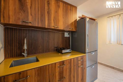 a kitchen with wooden cabinets and a stainless steel refrigerator at StayVista at Silver Slopes with outdoor pool in Chandīgarh