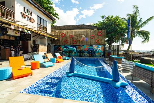 una piscina en un complejo con mesas y sillas coloridas en UNWND Boutique Hotel Camiguin, en Mambajao