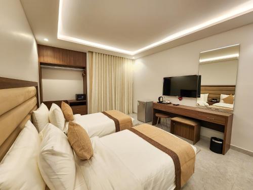 a hotel room with two beds and a desk and a television at Olaya Residence in Riyadh