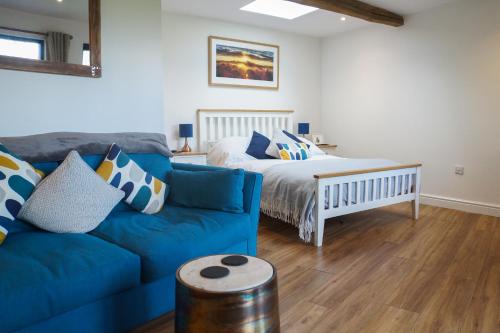a living room with a blue couch and a bed at Conkers - a new bespoke rural escape near Glastonbury in Glastonbury