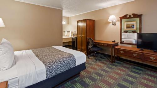 um quarto de hotel com uma cama e uma secretária com um computador em SureStay by Best Western Cameron em Cameron