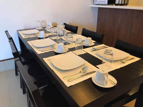 a long table with white plates and glasses on it at 2BR Penthouse in Anvaya Cove in Morong