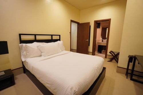 a bedroom with a large bed with white sheets and pillows at 2BR Penthouse in Anvaya Cove in Morong