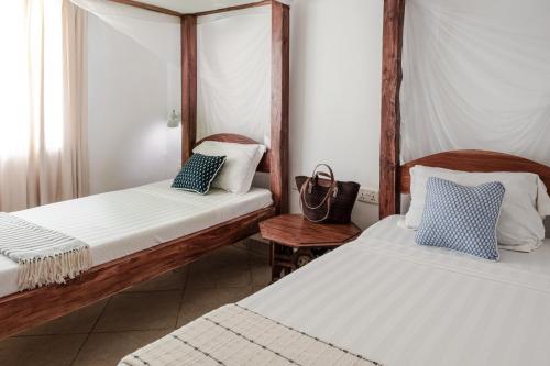 a room with two beds and a chair at Temple Point Resort in Watamu