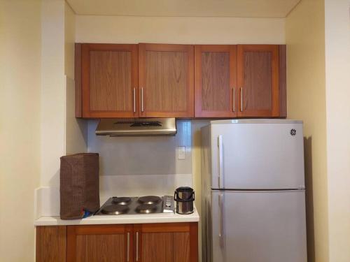 a kitchen with a white refrigerator and wooden cabinets at 2BR Penthouse in Anvaya Cove in Morong
