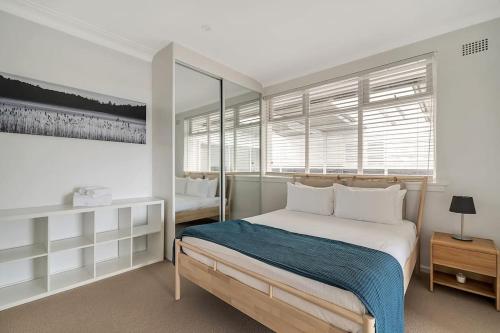 um quarto branco com uma cama e uma janela em LAGOON HOUSE // POOL // PET FRIENDLY em Bellambi