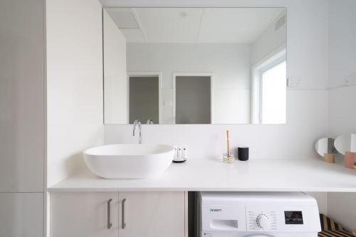 uma casa de banho branca com um lavatório e um espelho em LAGOON HOUSE // POOL // PET FRIENDLY em Bellambi
