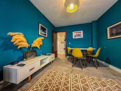 uma sala de estar com paredes azuis e uma mesa com cadeiras amarelas em Pisos Baza, Tres apartmentos en Baza Central em Baza