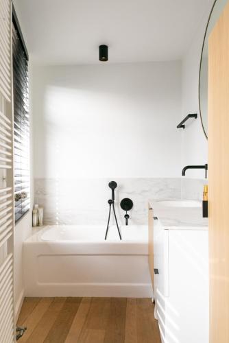 a white bathroom with a tub and a sink at In Sint Lambertus in Hasselt
