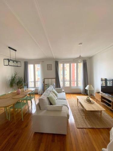 een woonkamer met een witte bank en een tafel bij Profitez de la golden hour depuis Levallois ! in Levallois-Perret