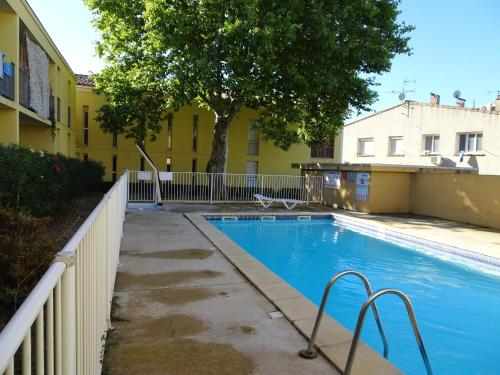 une piscine en face d'un bâtiment jaune dans l'établissement Appartement convivial à Aigues-Mortes, piscine partagée, à Aigues-Mortes