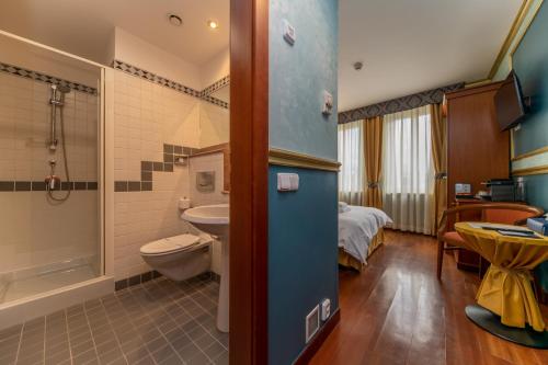 a bathroom with a sink and a toilet and a bed at Hotel Kinsky Fountain in Prague