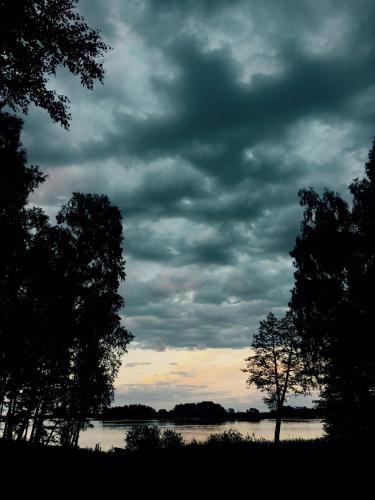 a cloudy sky over a body of water with trees at Island Beach House in Värmdö