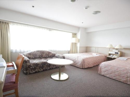 una camera d'albergo con due letti, un divano e un tavolo di The Gotembakan a Gotemba