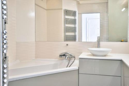 une salle de bain blanche avec une baignoire et un lavabo dans l'établissement Magnifique appartement 80 m2 face Tour Eiffel, à Paris