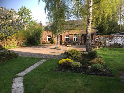 a house with a grass yard with a driveway at The Coach House at Riverlea in Blairgowrie