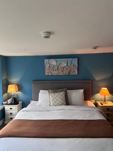 een slaapkamer met een groot bed met een blauwe muur bij The Townhouse in Miltown Malbay