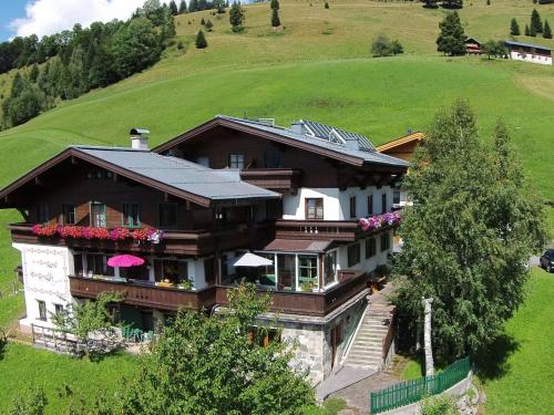 a large house on top of a green hill at Large Apartment in Maria Alm with Terrace in Maria Alm am Steinernen Meer