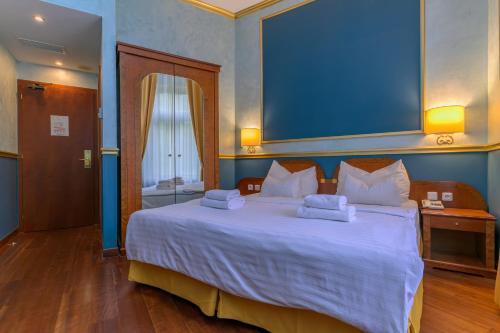 a bedroom with a large white bed with a blue wall at Hotel Kinsky Fountain in Prague