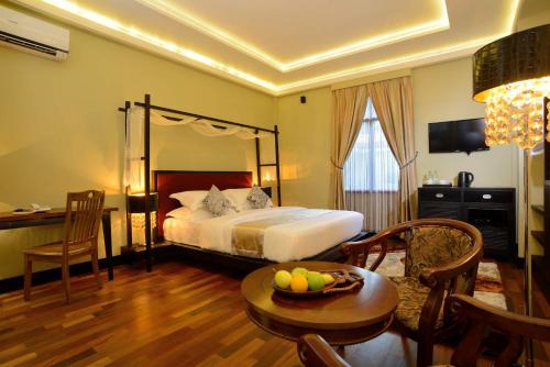Fuvahmulah Central Hotel في Fuvahmulah: غرفة في الفندق بها سرير وطاولة مع وعاء من الفواكه