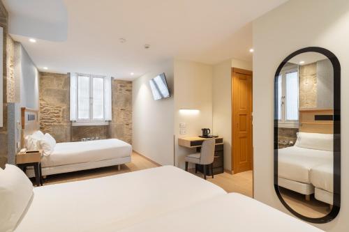 a hotel room with two beds and a mirror at Hotel Praza Quintana in Santiago de Compostela