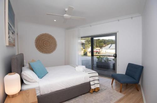 ein Schlafzimmer mit einem Bett und einem blauen Stuhl in der Unterkunft BREAKWATER VIEWS, Maloneys Beach in Maloney's Beach