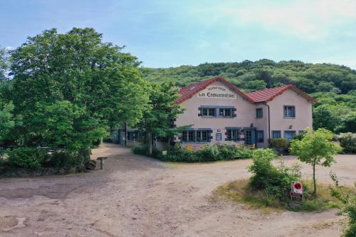 a building with a tree in front of a dirt road at Le Gite de Tournoel in Volvic