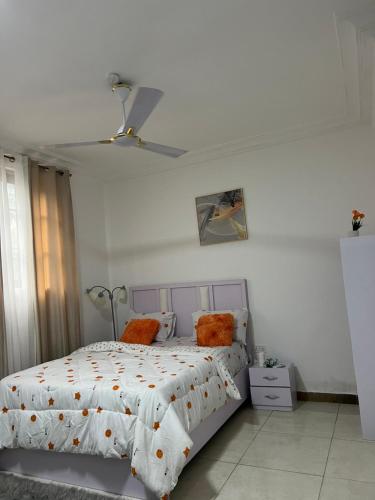 a white bedroom with a bed with orange pillows at Cozy Haven Suite in Accra