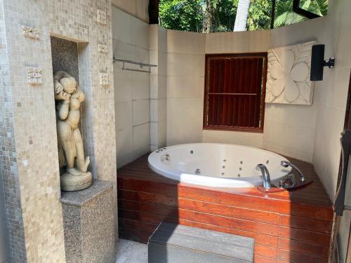 a bathroom with a tub with a statue of two at Tusita Wellness Resort in Paktako