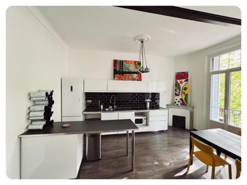a white kitchen with a table and a dining room at Appartement Bourgeois à 5 min à pied du centre in Cannes