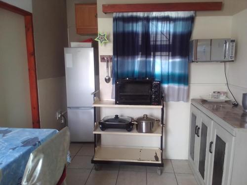 a kitchen with a refrigerator and some pots and pans at FEATHERS INN GUEST HOUSE in Walvis Bay