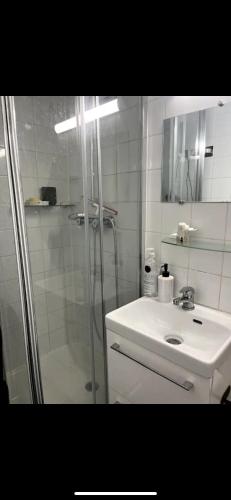 une salle de bain blanche avec une douche et un lavabo dans l'établissement Petit studio, Rue Daguerre, à Paris