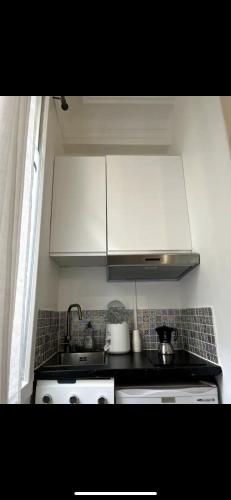 une cuisine avec des armoires blanches et un four à plaques de cuisson dans l'établissement Petit studio, Rue Daguerre, à Paris