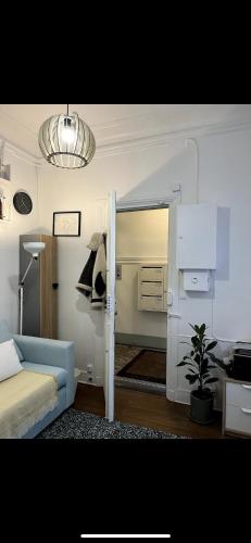 une chambre avec un canapé bleu et une pièce avec un miroir dans l'établissement Petit studio, Rue Daguerre, à Paris