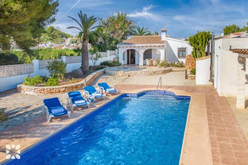 a swimming pool with chairs and a house at Villa Ananas by Abahana Villas in Moraira