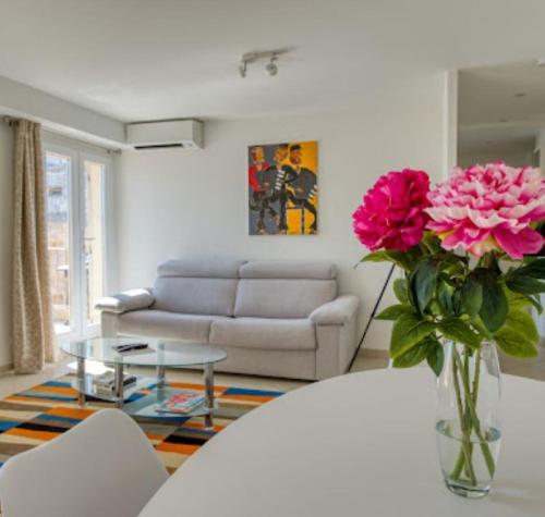 - un salon avec un canapé et un vase orné de fleurs roses dans l'établissement Grand deux pièces - Hyper Centre, à Nice