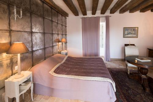 een slaapkamer met een groot bed en een tafel bij Le Prieuré de Loups in Saint-Michel-en-Brenne