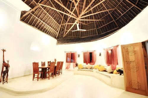 uma sala de estar com um tecto grande e uma mesa em 3 bedrooms house at Watamu 100 m away from the beach with shared pool furnished terrace and wifi em Watamu