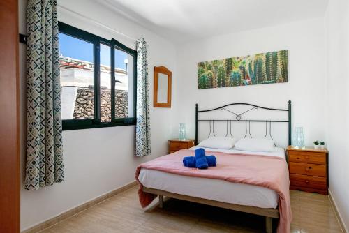 a bedroom with a bed with a pink blanket and a window at Apartamentos Bella Vista in Puerto del Carmen