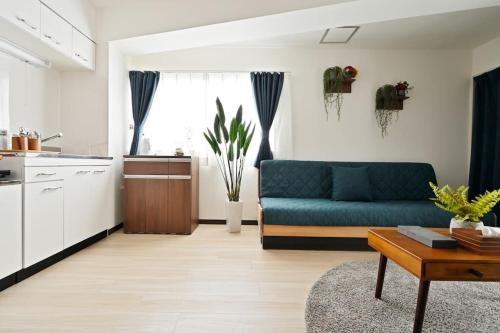 uma sala de estar com um sofá azul e uma cozinha em シティマインド京町303 em Osaka
