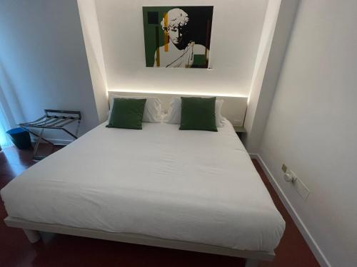 a small bedroom with a white bed with green pillows at Ottanta5 Private Rooms in Messina