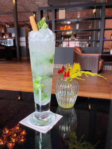 a drink in a glass on a table with a vase at Titanic Hotel Liverpool in Liverpool