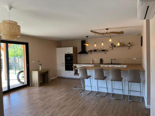 une cuisine avec un comptoir et quelques tabourets de bar dans l'établissement Location Jolie Villa située au calme avec piscine à Lacanau océan, à Lacanau