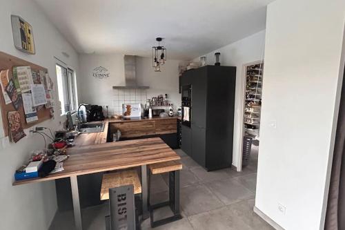 eine Küche mit einem Holztisch und einem schwarzen Kühlschrank in der Unterkunft Maison récente 3 chambres dont 1 suite parentale in Saint-Sauveur-dʼAunis